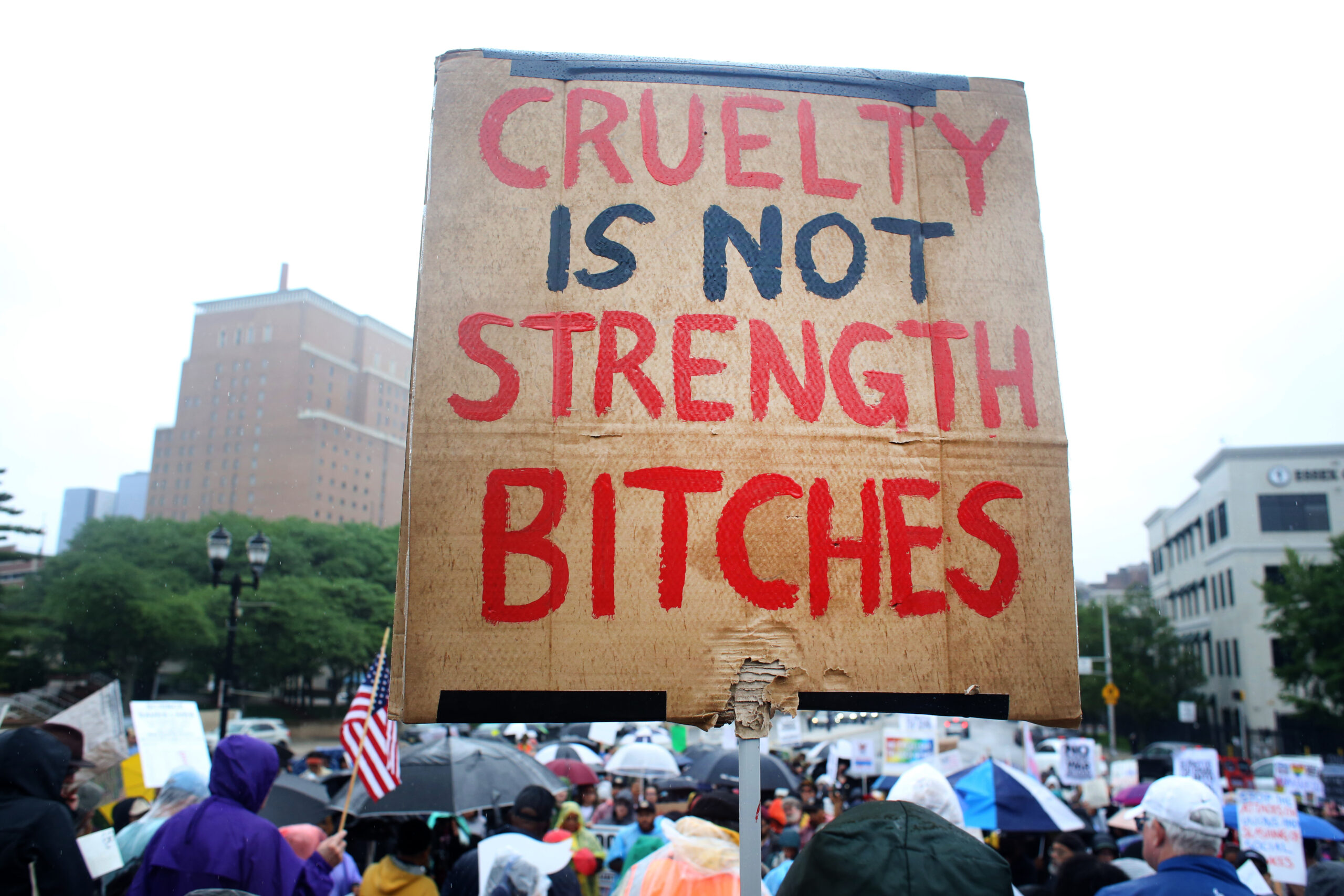Sign at the Newark No Kings rally written in red and black on cardboard that reads "CRUELTY IS NOT STRENGTH BITCHES."