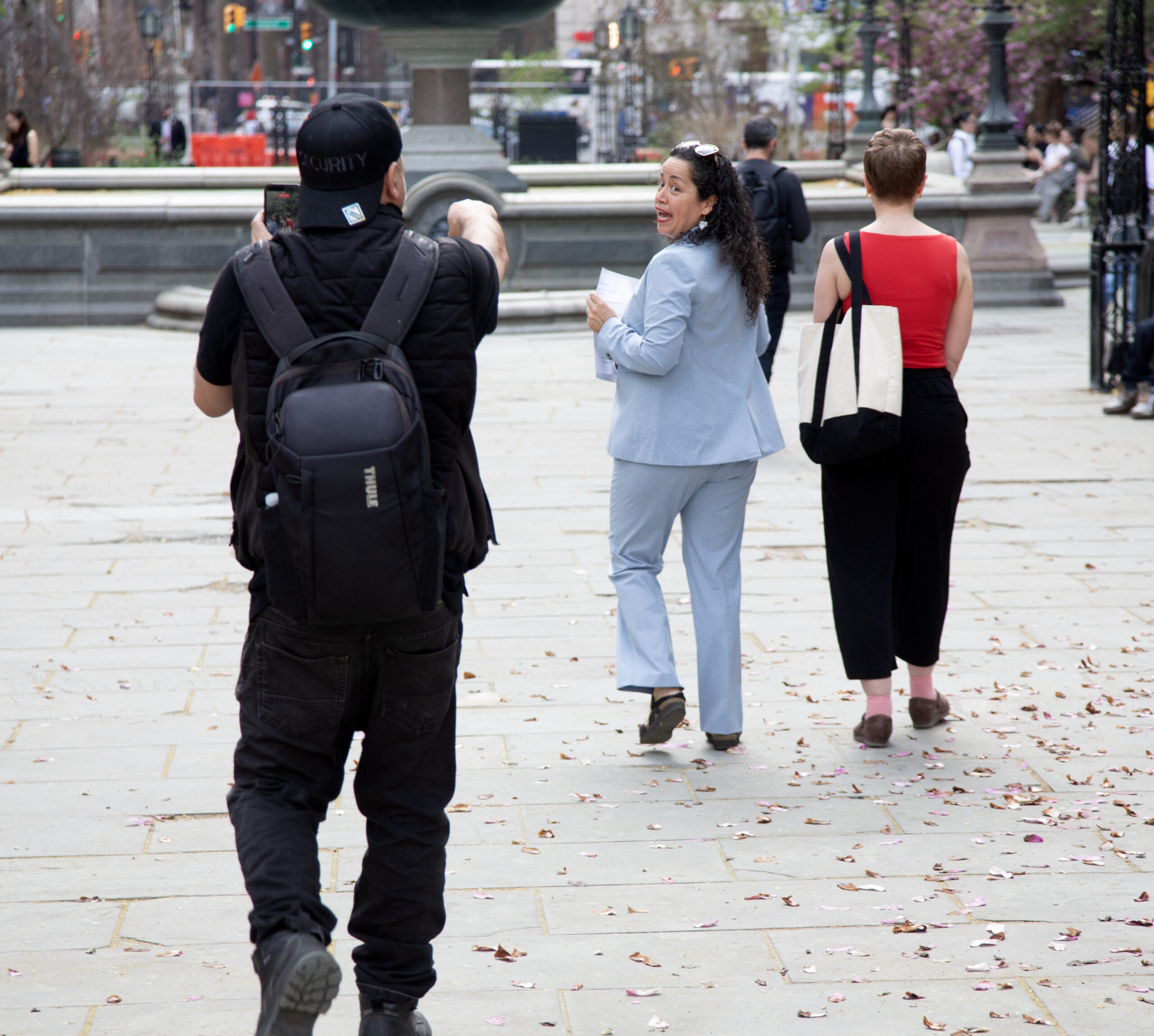 Alexa Avilés turns to call back over her shoulder at a heckler who's following her, recording her on a phone, as she leaves the AI Moratorium rally in City Hall Park.