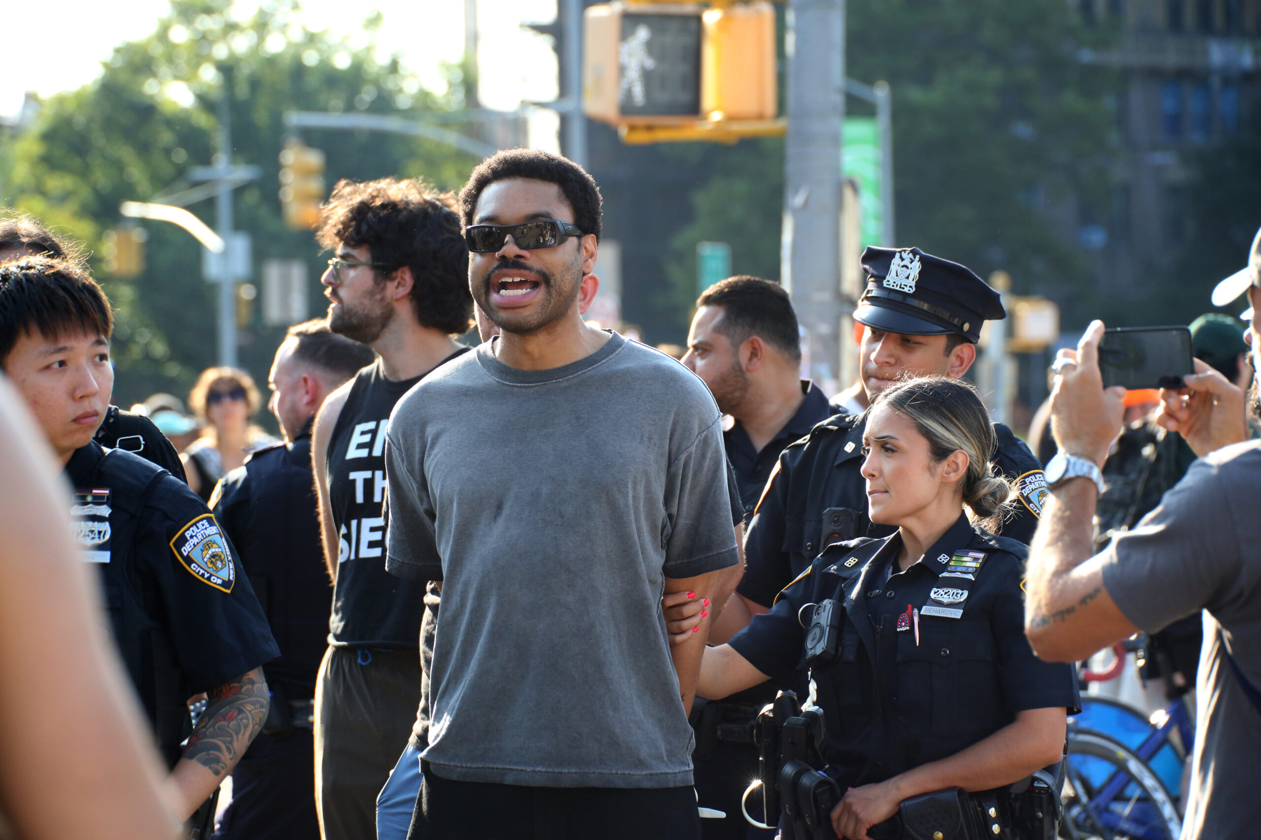 Eon Huntley, arrested at the Families Stand With Gaza rally, continues chanting as cops lead him towards the camera. His hands are tied behind his back.