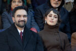 Zohran Mamdani and Rama Duwaji sitting at the inauguration. He's smiling. She's gazing towards the camera with her head tilted and a look of quiet regard? judgement? amusement? on her face.