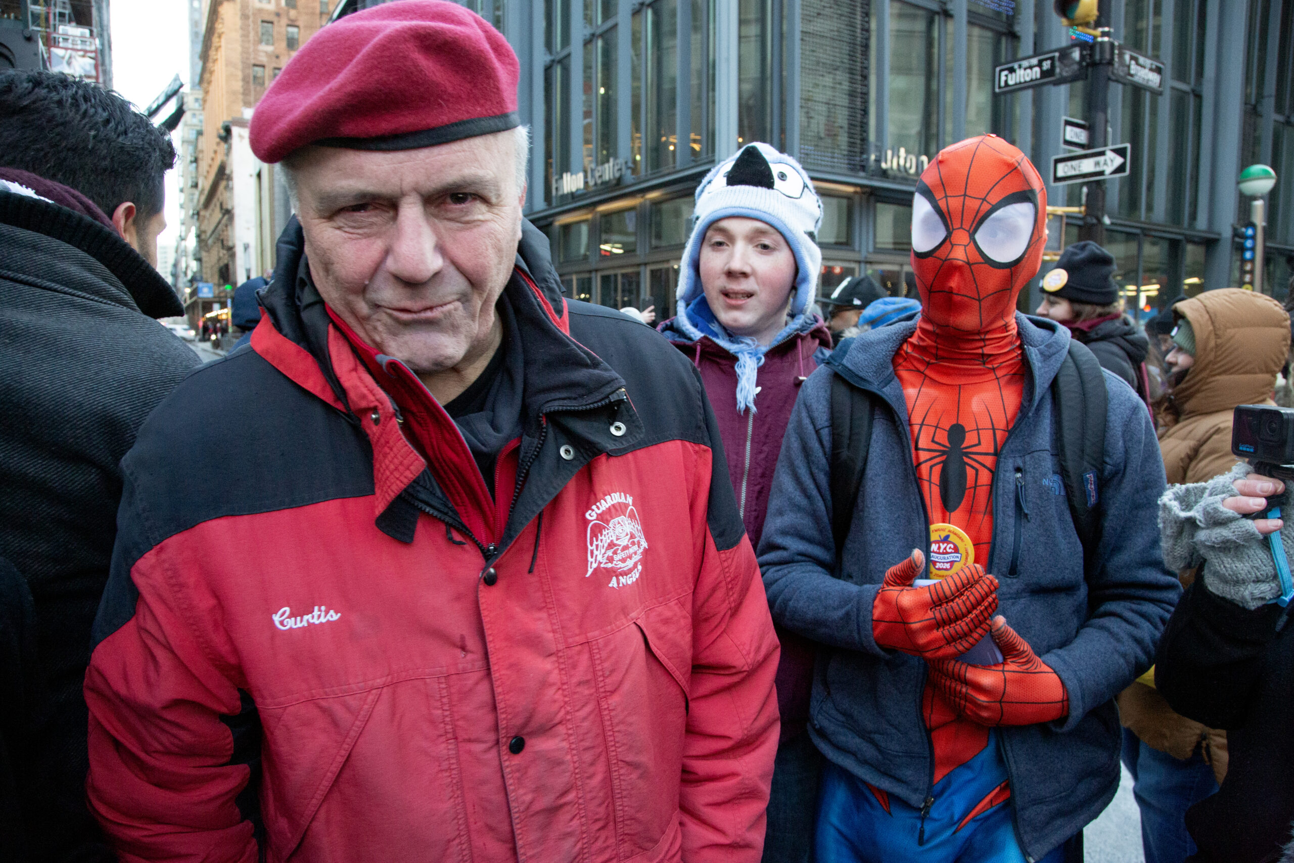 Curtis Sliwa smiles at the camera at Fulton and Broadway after the inauguration. A person dressed as Spider-Man stands behind him.